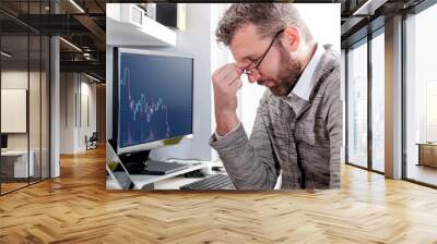 Depressed investor analyzing crisis stock market with graph on screen at home office Wall mural