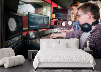 Music engineer and musician working together in recording studio using mixing desk Wall mural