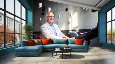 Senior businessman shaking hands during meeting in cafe Wall mural