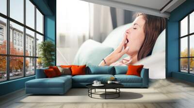 Sleepy young woman lying on couch and relaxing at home. Casual style indoor shoot Wall mural