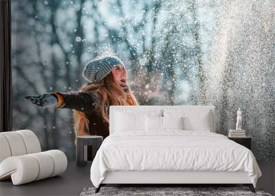 Smiling woman throwing snow in the air at sunny winter day Wall mural