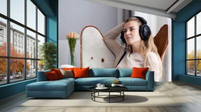 Woman at home wearing headphones while using digital tablet, listening to audiobooks or music Wall mural