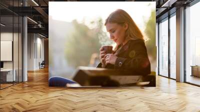 Woman smelling and drinking hot coffee, autumn sunset at the street Wall mural