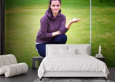 Young woman golf player holding ball near cup Wall mural