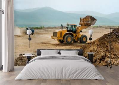 Loading earth soil into the side of a cargo dump truck with a front loader bucket Wall mural