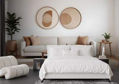 A Scandinavian-style home interior design of a modern living room includes a beige sofa and a wooden round coffee table against a white wall with two frames Wall mural