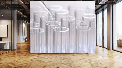 Pipette adding fluid to one of several test tubes Wall mural