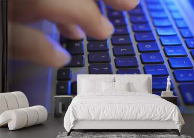 Typing on laptop computer with blue light Wall mural