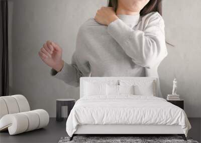 Woman feeling pain on shoulder over gray background Wall mural