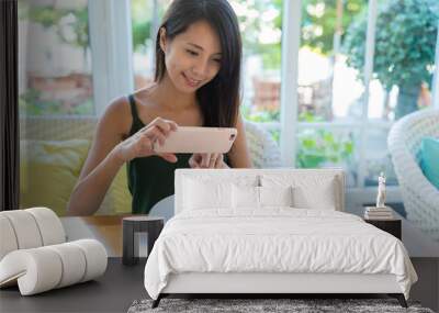 Woman taking photo with cellphone on her dish in restaurant Wall mural