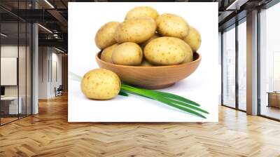 Raw unpeeled potatoes in a wooden bowl and green onions, isolated on white background. Wall mural