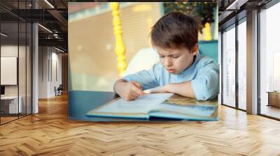 Boring and tired little boy reading book Wall mural