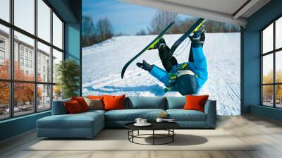 Boy with cross-country skis lying on snow Wall mural