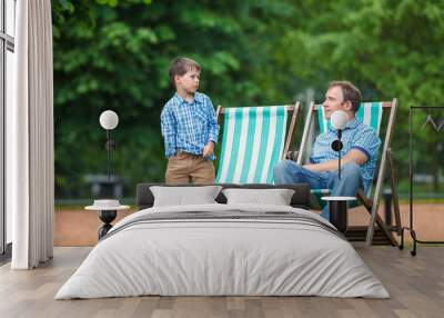 Happy father and son having rest in city park on summer day Wall mural