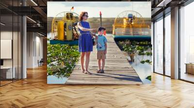 Young mother with her little son on an airboat tour. The Everglades are a natural region of wetlands in the southern portion of the U.S. state of Florida, USA. Wall mural