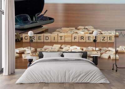 credit freeze word or concept represented by wooden letter tiles on a wooden table with glasses and a book Wall mural