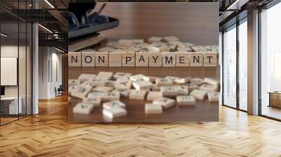 non payment word or concept represented by wooden letter tiles on a wooden table with glasses and a book Wall mural