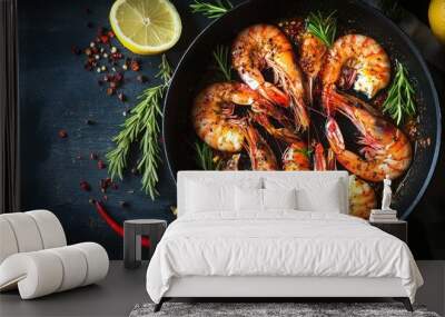 Close-up of cooked shrimp with lemon and rosemary in a frying pan on a dark background. Wall mural