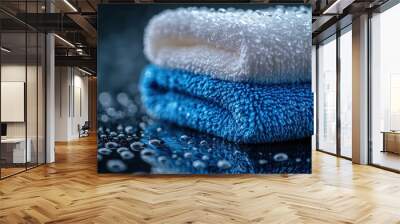 Two folded towels, one blue and one white, on a wet surface. Wall mural