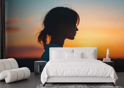 A womana silhouette blending with the soft light of a sunset. Wall mural