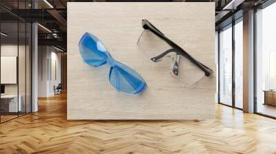 Safety glasses on wooden background, top view Wall mural