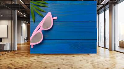 Stylish pink sunglasses on wooden background, top view. Summer concept Wall mural