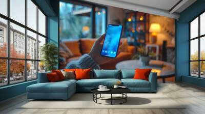 Close-up of hands holding mobile phone in living room at home Wall mural