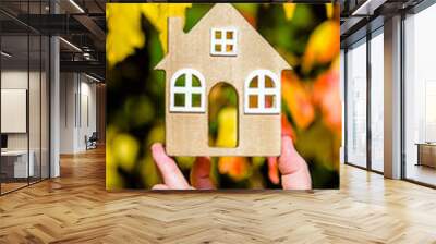 The symbol of the house in the girl's hand on the background of yellow leaves
 Wall mural