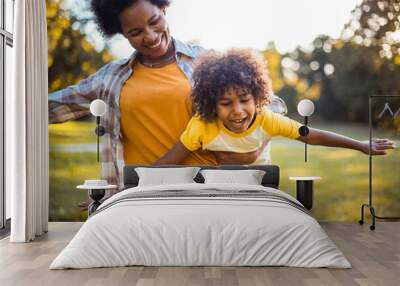  African American mother and daughter running trough park. Focus on little girl. Wall mural