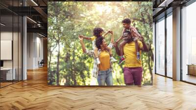 African American family walking trough park. Parents carrying children on piggyback. Wall mural