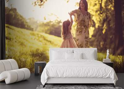 Beauty little girl with her Mother playing at nature. Wall mural