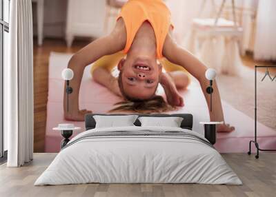 Little girl doing a workout in the bedroom at home. Wall mural