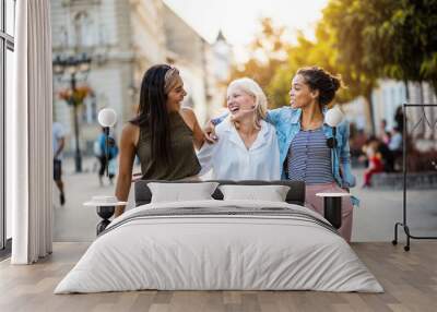 Three young women walking together on city street. Wall mural