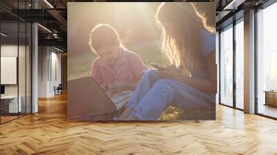 Two little girls using technology in nature. Wall mural