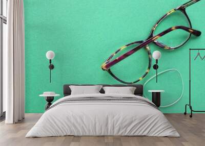 Old broken eyeglasses with damaged lens on green background. Poor eyesight. Reuse and repair concept. Idea of health. Failure optic eyewear. Breakage of vision correction glasses. Close up, flat lay Wall mural