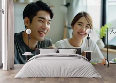 A japanese couple happily enjoying a meal together at home, white clean modern living room Wall mural