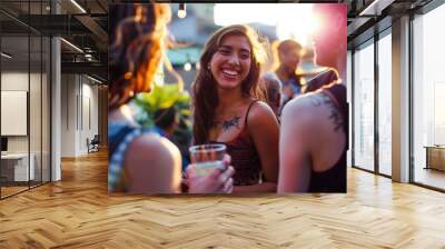 Young woman smiling and enjoying a lively evening with friends at an outdoor gathering under warm, festive lights Wall mural