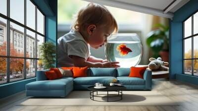 Curious toddler and fish. A toddler leans in close, fascinated by a vibrant orange Betta fish swimming in a small round fishbowl, with a stuffed toy nearby. Wall mural