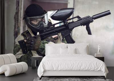 Shot of soldier in paintball mask with weapon in his arms Wall mural