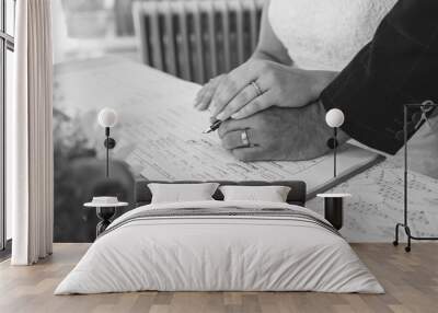 a bride and groom signing a dummy register at a wedding while displaying wedding rings Wall mural