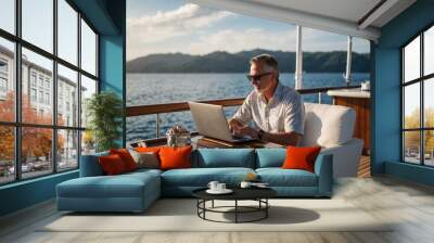  A mid-age male working on laptop computer on deck of a luxury yacht. Remote working concept Wall mural