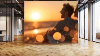 A couple sits by the ocean, enjoying a golden hour sunset. The scene embodies peace, romance, and beauty, with the tranquil water and glowing sunlight. Wall mural