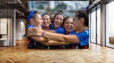 A delighted female soccer team embracing each other and smiling broadly in a joyous celebration after a successful game on the field. Wall mural