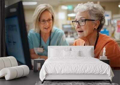 Two nurses, one elderly and one younger, engage with a computer screen in a clinic, displaying teamwork and collaboration in a medical setting environment. Wall mural