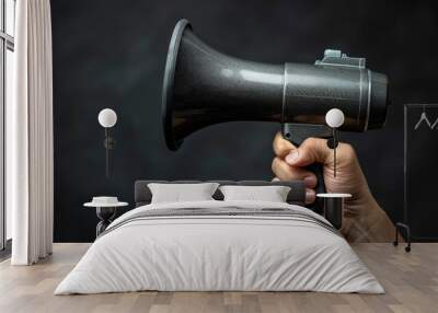 Hand holding a megaphone against dark background Wall mural