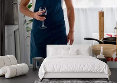  man in apron walking through kitchen with glass of wine Wall mural