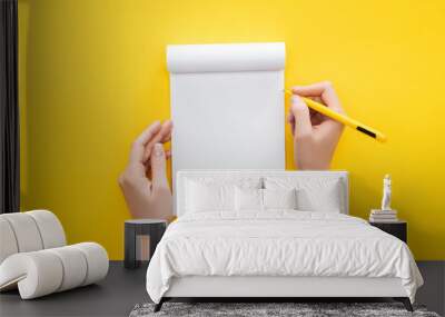  partial view person holding pen over blank notebook on yellow background Wall mural