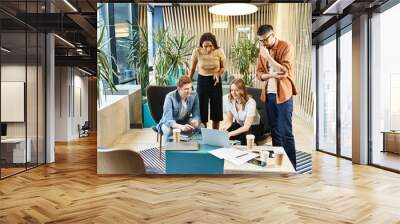 A diverse group of coworkers collaborate and discuss ideas around a table in a contemporary office setting. Wall mural