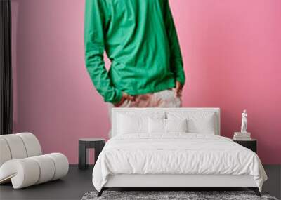 A dreamy young African American man in casual wear and curly hair posing in front of a pink background. Wall mural