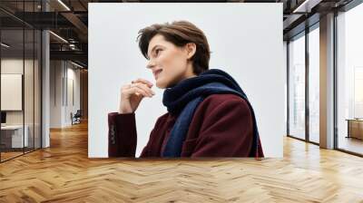 A fashionable woman dressed in warm winter attire thoughtfully gazes off, exuding calm elegance. Wall mural